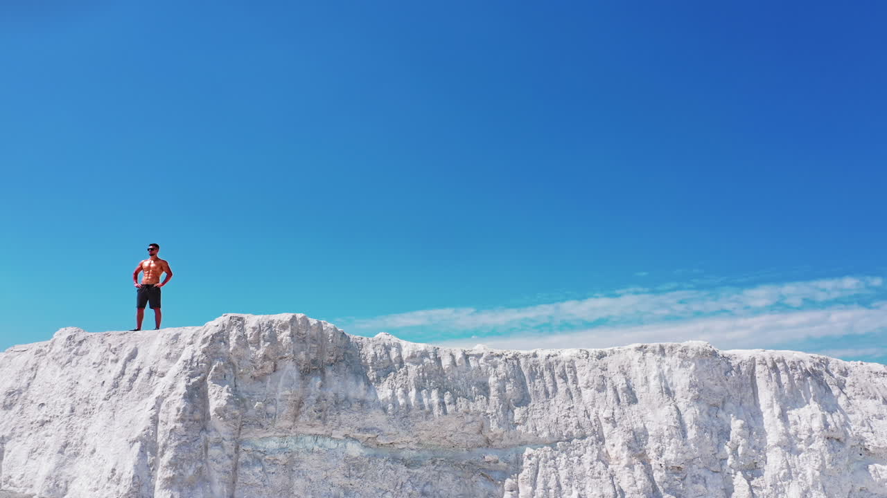 Sportsman standing on cliff of mountain. Man with naked torso standing on top of mountain and enjoying nature
