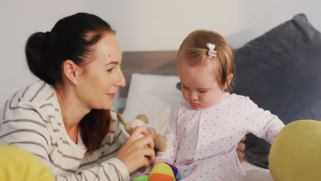 caucasian mother and baby playing with toys on the bed at home