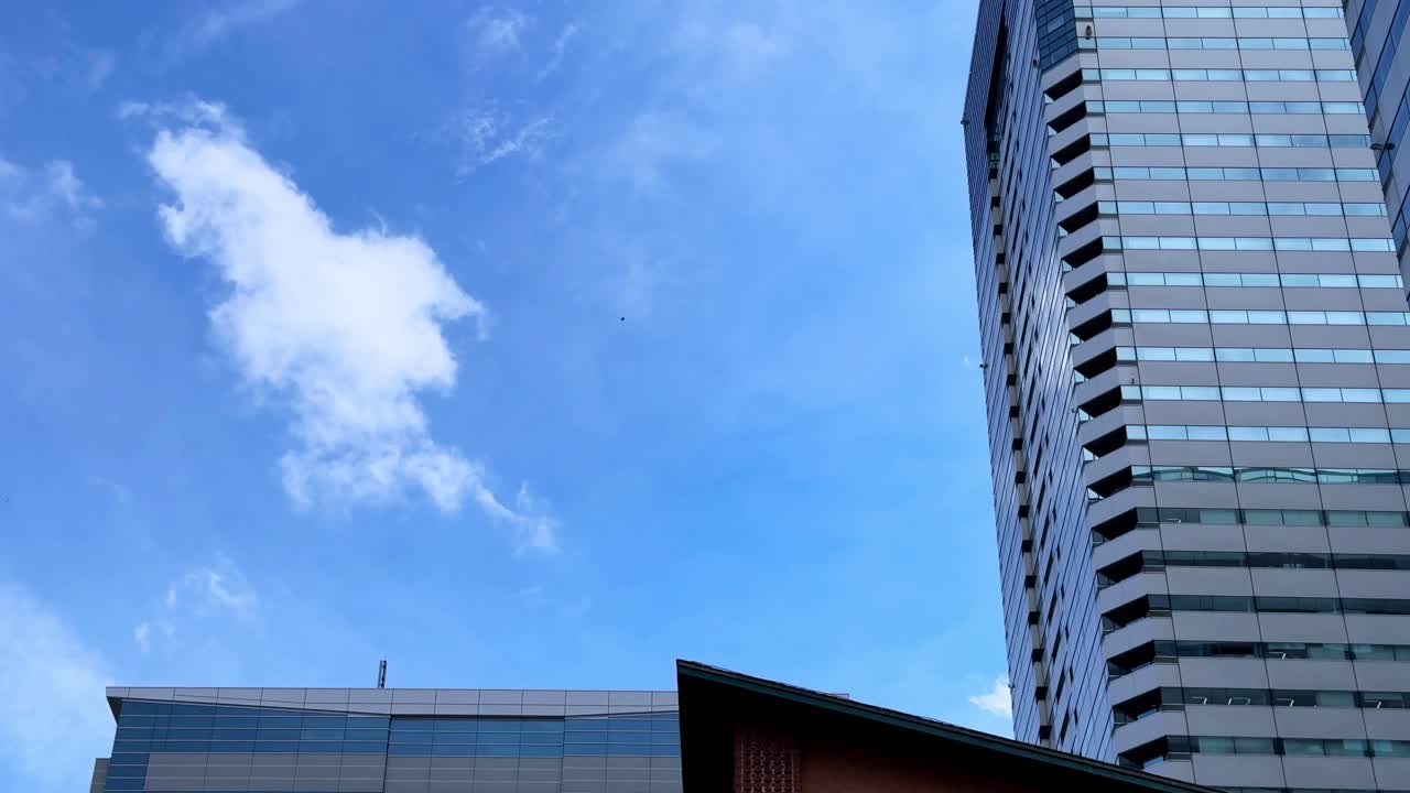 Tall modern buildings against a clear blue sky with light clouds on a sunny day