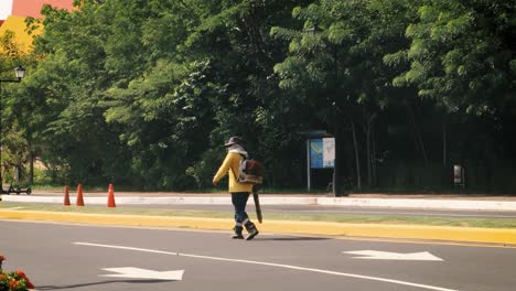 Civil-public-city-specialist-utilizing-mechanical-leaf-blower-to-uproot-the-recently-cut-grass-into-the-side-of-the-road-to-facilitate-the-labor-of-picking-it-up-and-moving-it-to-a-squander-land