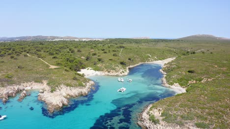 secluded cove along the coastline of menorca with yachts anchored in the shallow waters