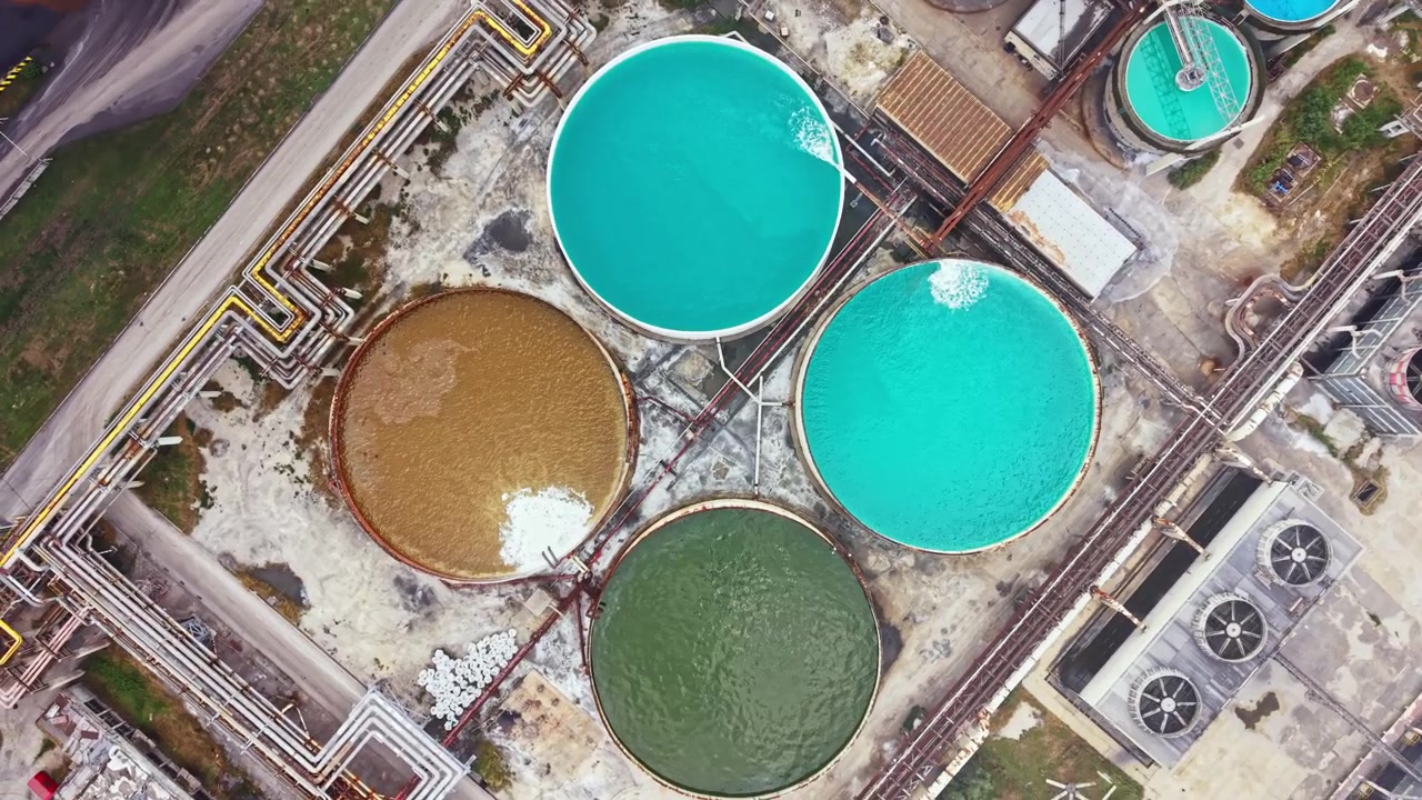 Water treatment facility shows large tanks with different colors of water in a technology setting during daytime