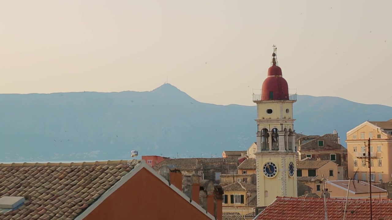 Panoramica verso il basso dal cielo al tramonto al campanile della Chiesa di San Spiridione nella Città Vecchia di Corfù, Grecia.