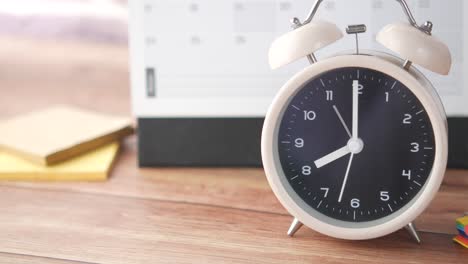 alarm clock on a desk with calendar and stationery