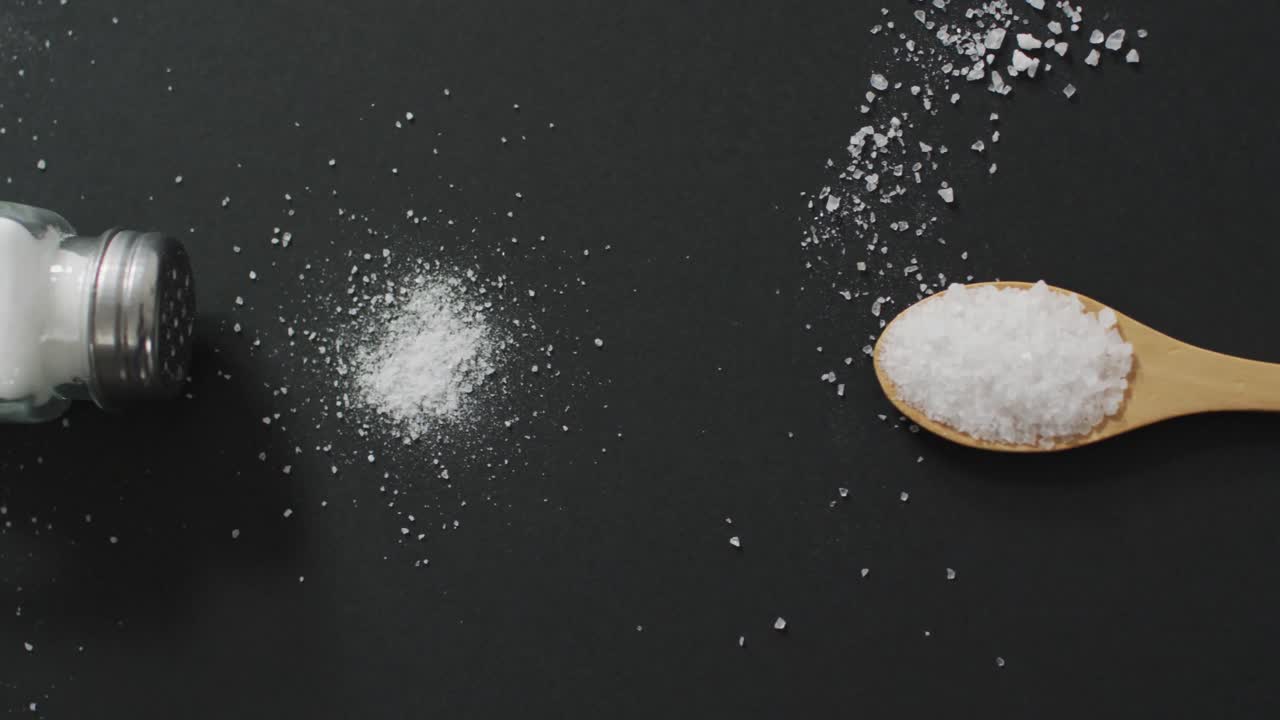 video de sal en un batidor de sal y una cuchara sobre fondo negro