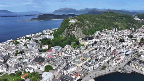 drone shot of picturesque alesund norway on sunny summer day, city buildings, green hill and islands all over bay 60fps