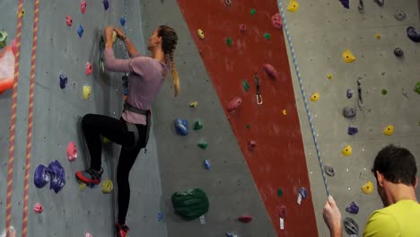 Coach-assisting-a-woman-in-climbing-the-artificial-wall-4k