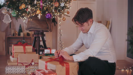 Happy-tying-ribbon-on-wrapped-gift-box-at-home-during-Christmas