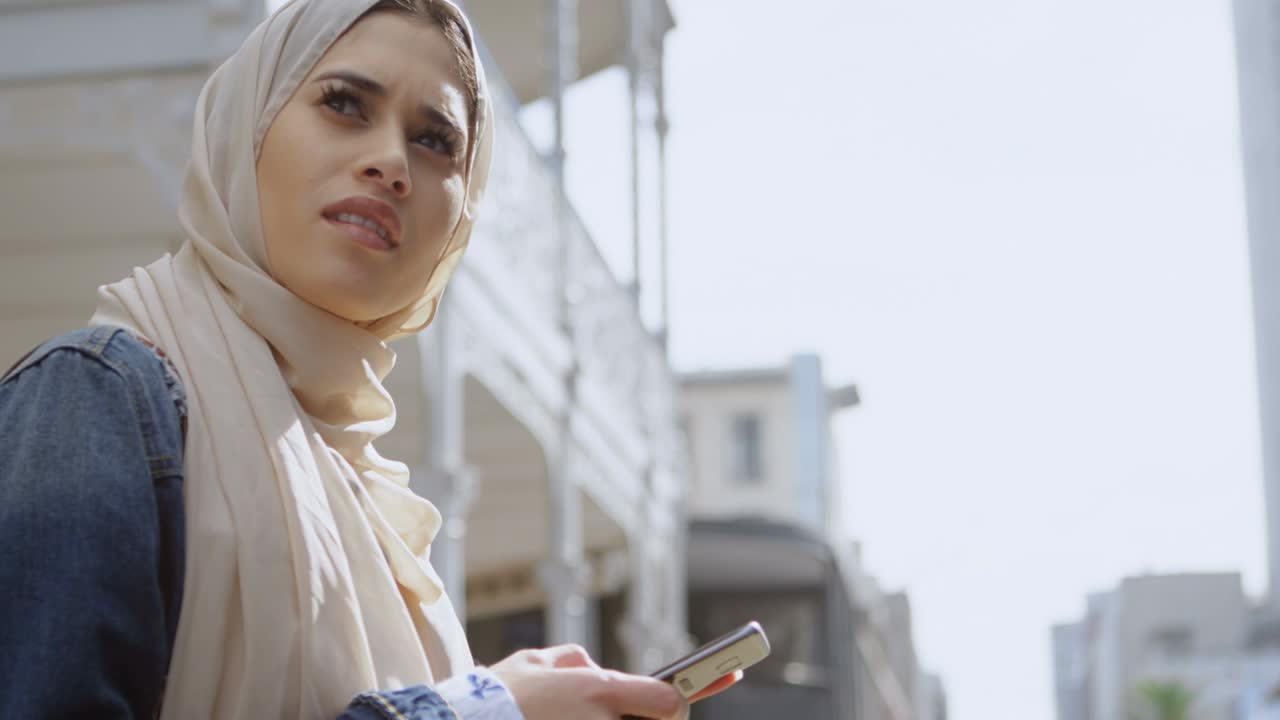 анимация азиатской женщины в хиджабе, сидящей и использующей смартфон над городским пейзажем