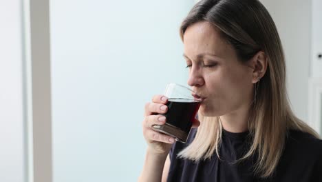 woman drinking beverage near a window