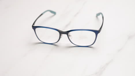 detail of blue prescription glasses on a light background