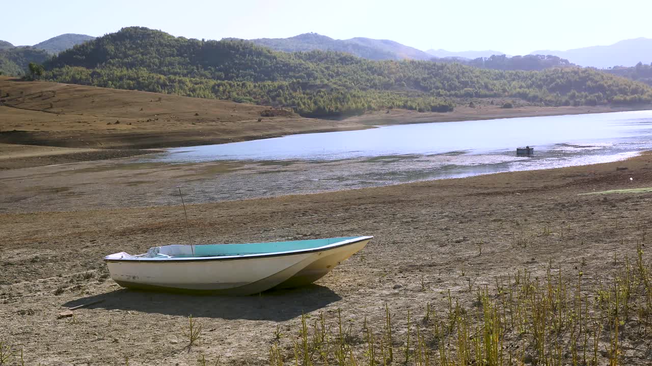A boat resting on a dry lake bed, revealing the effects of drought and low water levels.