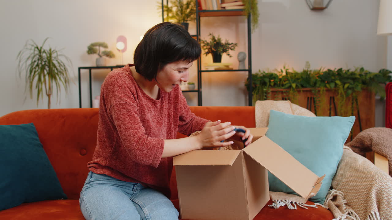 Happy woman unboxing new parcel with gadget wireless headphones delight through ecommerce shopping