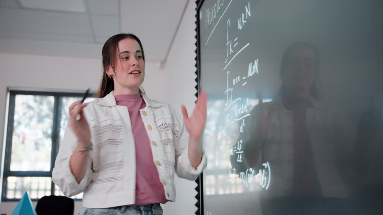 A teacher explaining physics on the whiteboard in a classroom