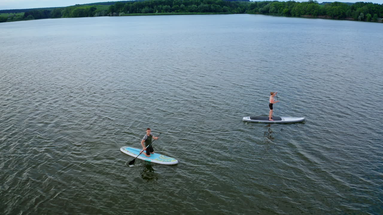 Two Persons On Paddle Board. Drone view of couple on sup paddle boards