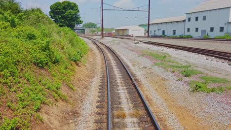 view of railroads tracks from behind a train as it passes on a summer day