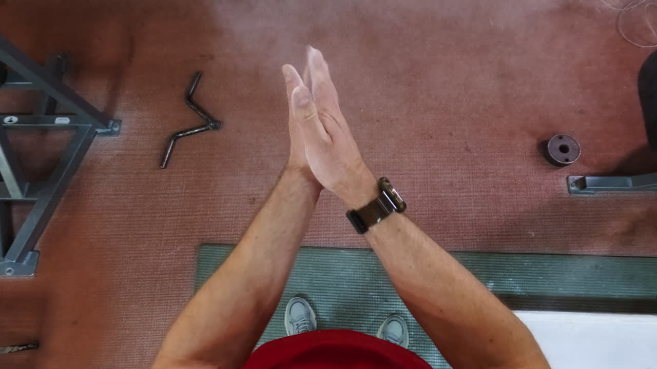 First-Person View of Hands Clapping with Chalk in a Gym