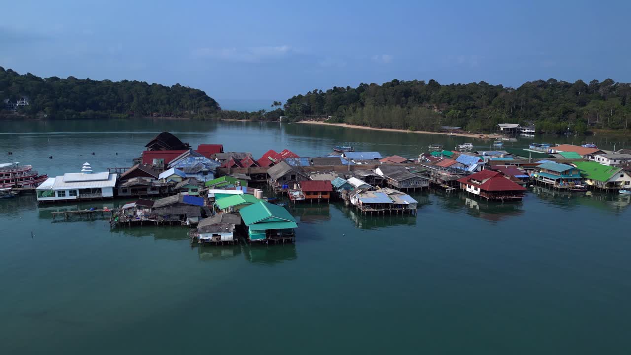 Bang Bao Pier floating village in Koh Chang island, Thailand, showing colorful houses and boats sailing in turquoise water. Unbelievable aerial view flight