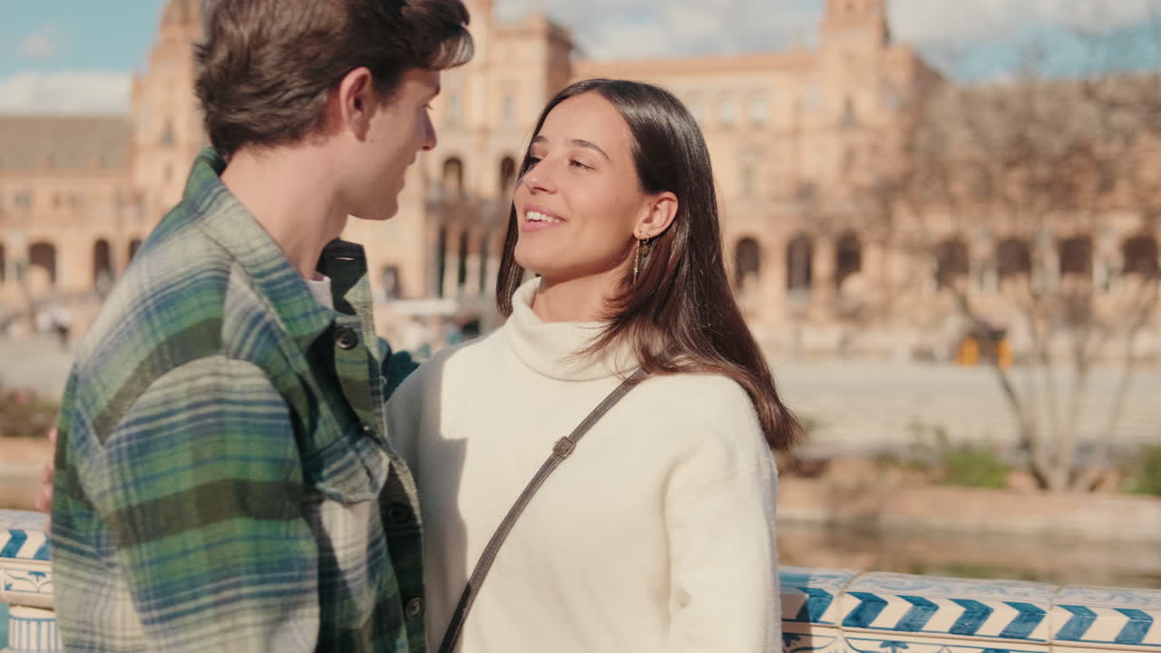 Happy young couple man and woman kissing while standing on bridge