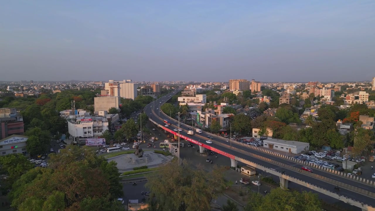 Riprese drone che mostrano l'autostrada Mumbai-Agra NH60 vicino a Mumbai Naka a Nashik, Maharashtra, con skyline urbano, edifici residenziali, traffico su strada sopraelevata e vegetazione circostante durante il giorno.