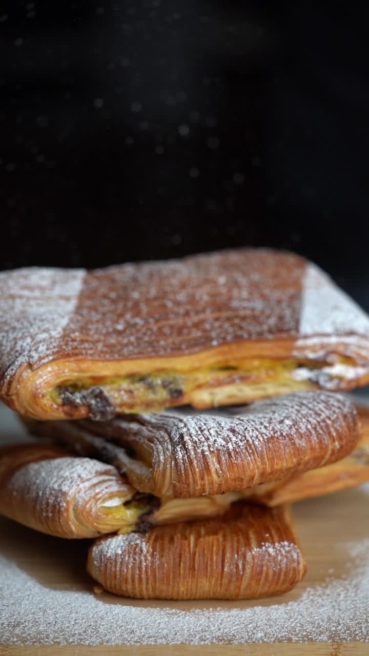 A chief adds salt to croissant pastry filled with cream and chocolate, close up shot, insert shot