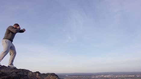 man exercising on mountain top with city view