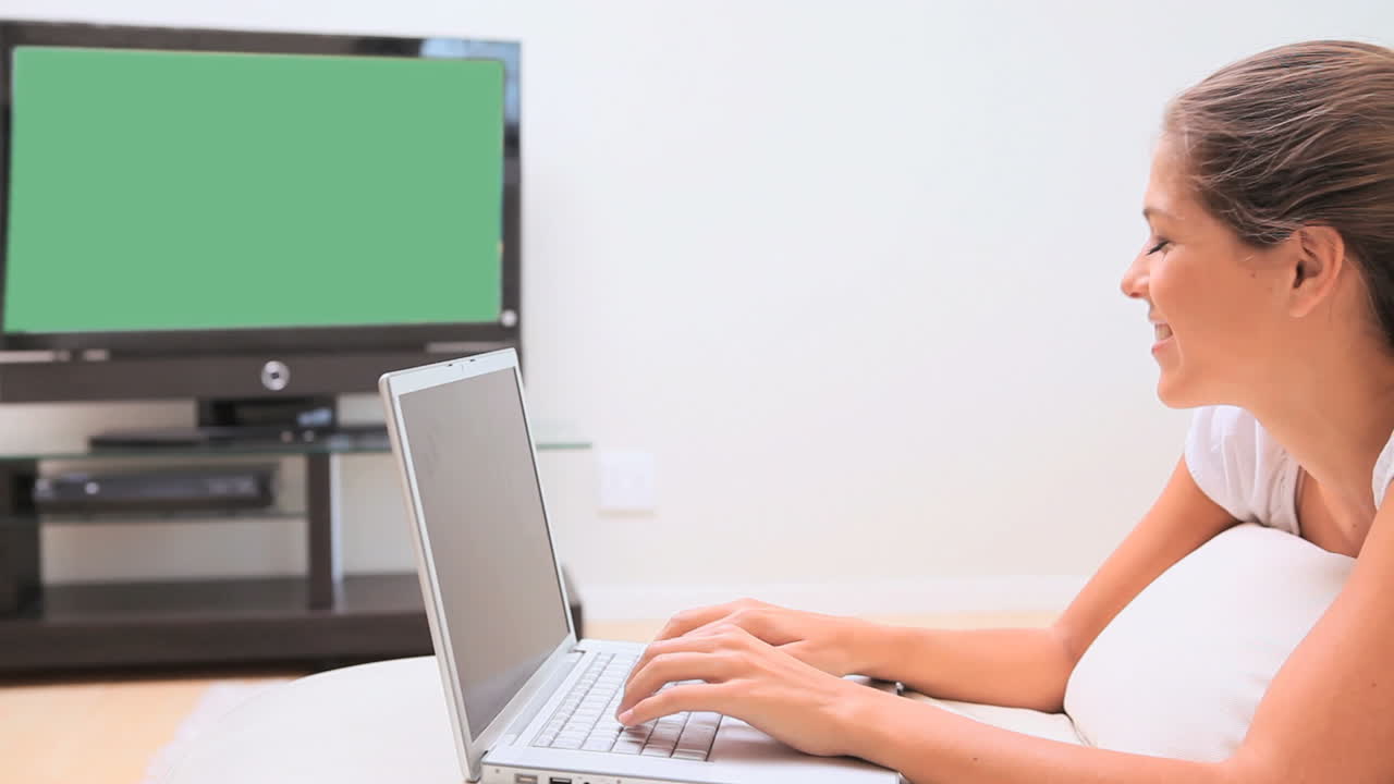mujer sonriente escribiendo en una computadora portátil