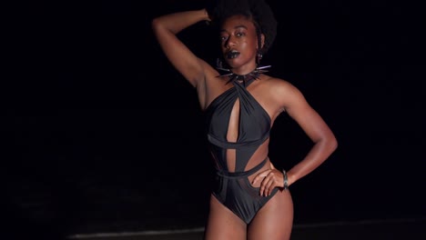 A-black-young-woman-in-a-sexy-bikini-enjoys-a-night-on-the-beach-with-ocean-waves-in-the-background