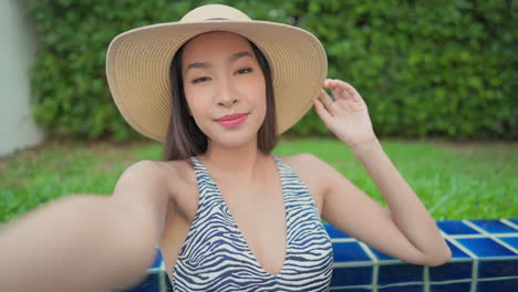 POV-of-a-beautiful-young-Asian-woman-in-zebra-print-bathing-suit-takes-a-selfie-video-inside-a-pool