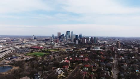 orbiting drone shot of minneapolis skyline with residential neighborhoods and major freeway in foreground
