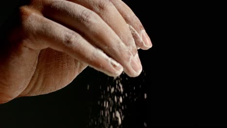 a man sprinkles flour and gets it off his fingers