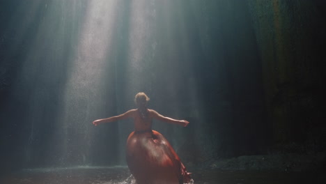 happy woman dancing in waterfall cave splashing water wearing beautiful dress enjoying nature dance feeling spiritual freedom 4k