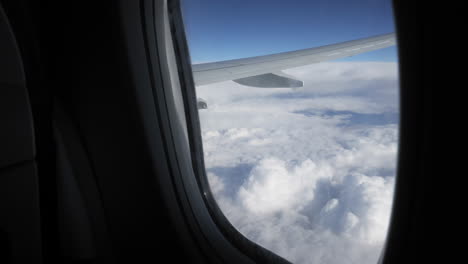 looking out the window of a commercial airplane at puffy clouds