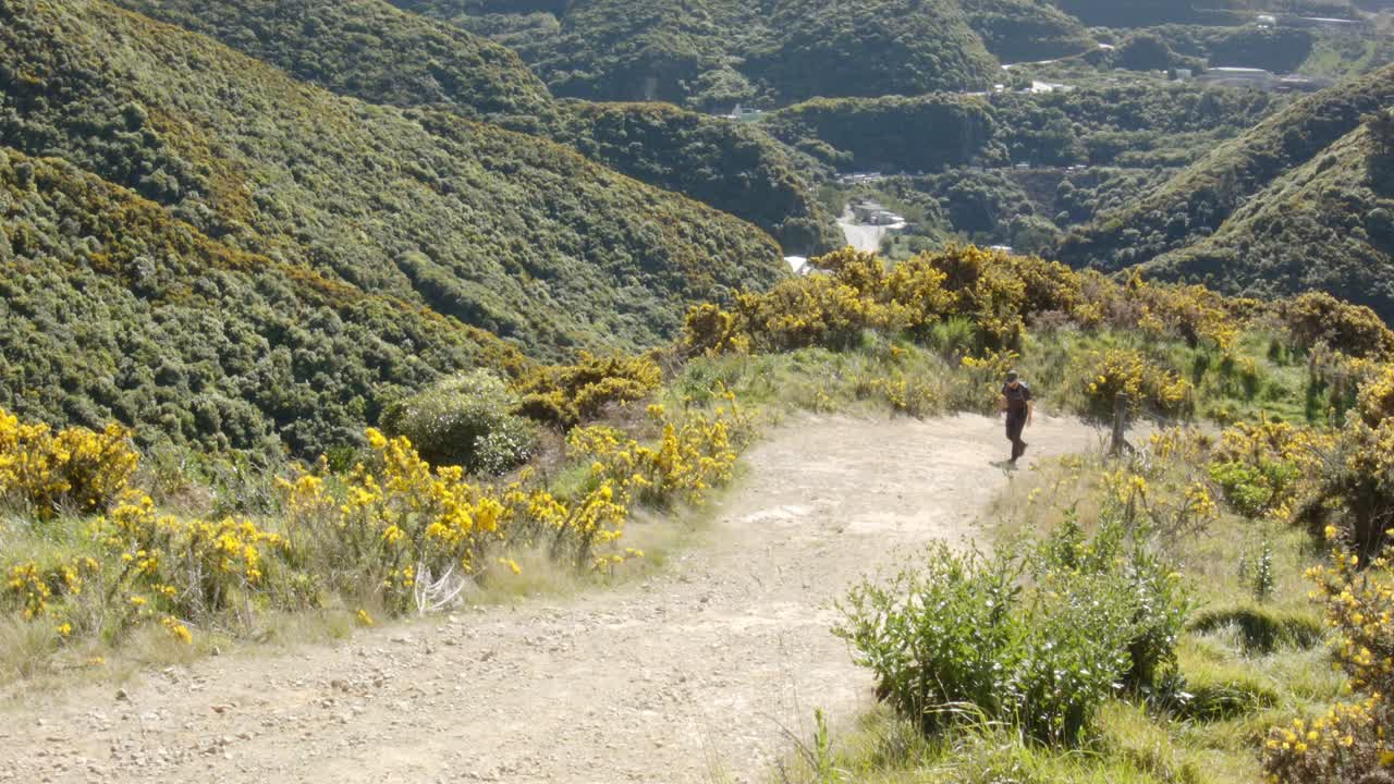 un excursionista de un día caminando por un sendero de grava empinado con un valle en el fondo