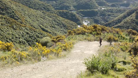 un excursionista de un día caminando por un sendero de grava empinado con un valle en el fondo