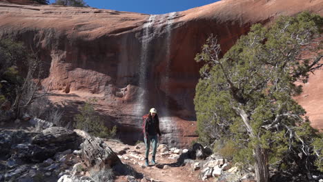 excursionista femenina caminando por senderos bajo una cascada en el parque del monumento nacional de colorado, ee.uu.