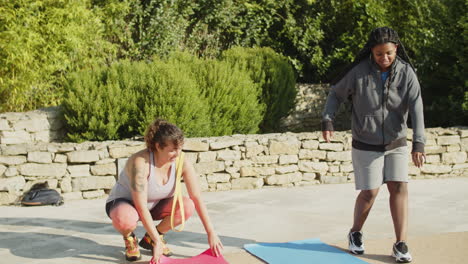 long shot of fat women laying exercise mat for outside workout