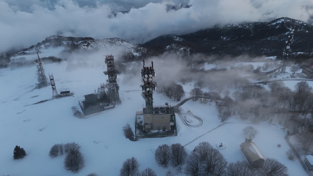 estación de radio con mástiles de transmisor en la montaña nevada en la niebla de invierno