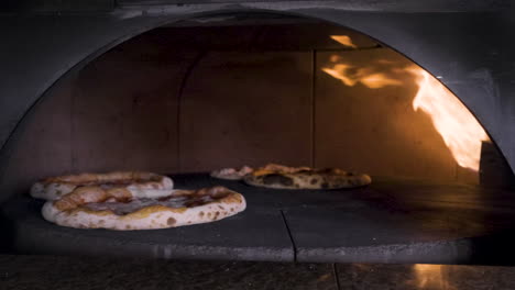 pizzas spinning in the stone oven in a restaurant kitchen