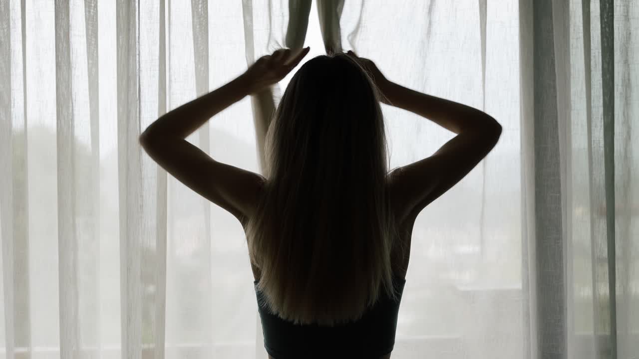 창문을 통해 바라보는 현대 호텔에서 서있는 여성의 커튼 레이스 오픈의 뒷면 전망