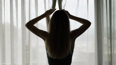 vista trasera de la mujer abriendo la cortina de encaje de pie en un hotel moderno mirando a través de la ventana