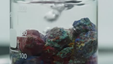 experiment observing the interaction of colorful mineral rocks with water in a laboratory environment - a close-up visual study of physical and chemical changes