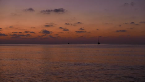 Sonnenuntergang-über-Dem-Mittelmeer-Mit-Zwei-Kleinen-Booten-Und-Einem-Springenden-Fisch-Als-Silhouette