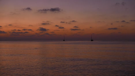 puesta de sol sobre el mar mediterráneo con dos pequeños barcos y un pez saltando en silueta