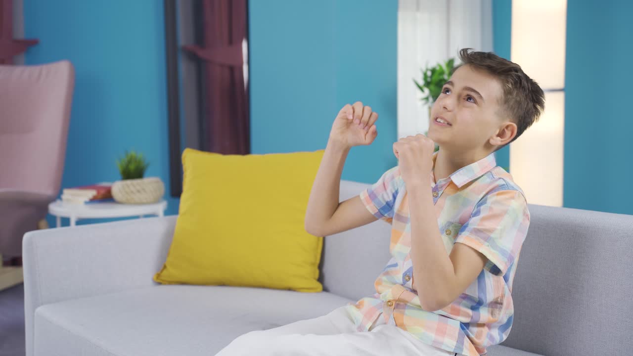 의자에 앉아 있는 어린 소년은 성공의 기 ⁇ 을 경험하고 있습니다.