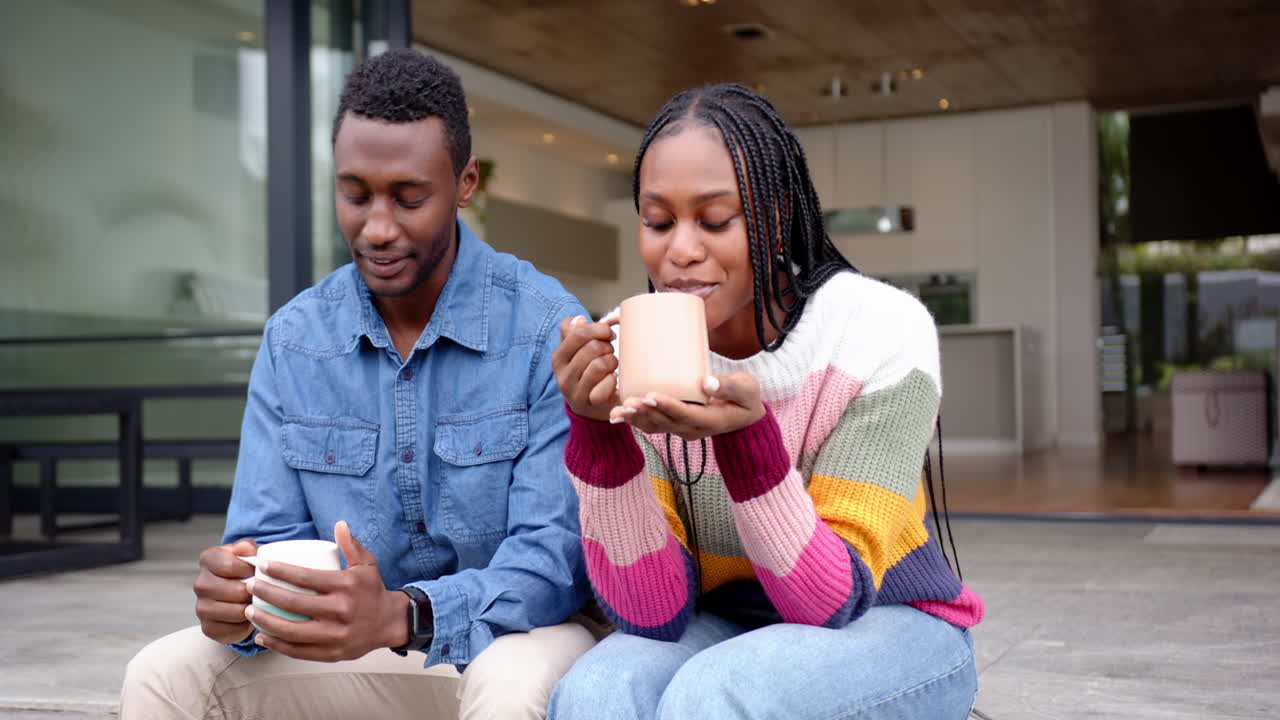 Drinking coffee, young african american couple sitting together and enjoying conversation at home