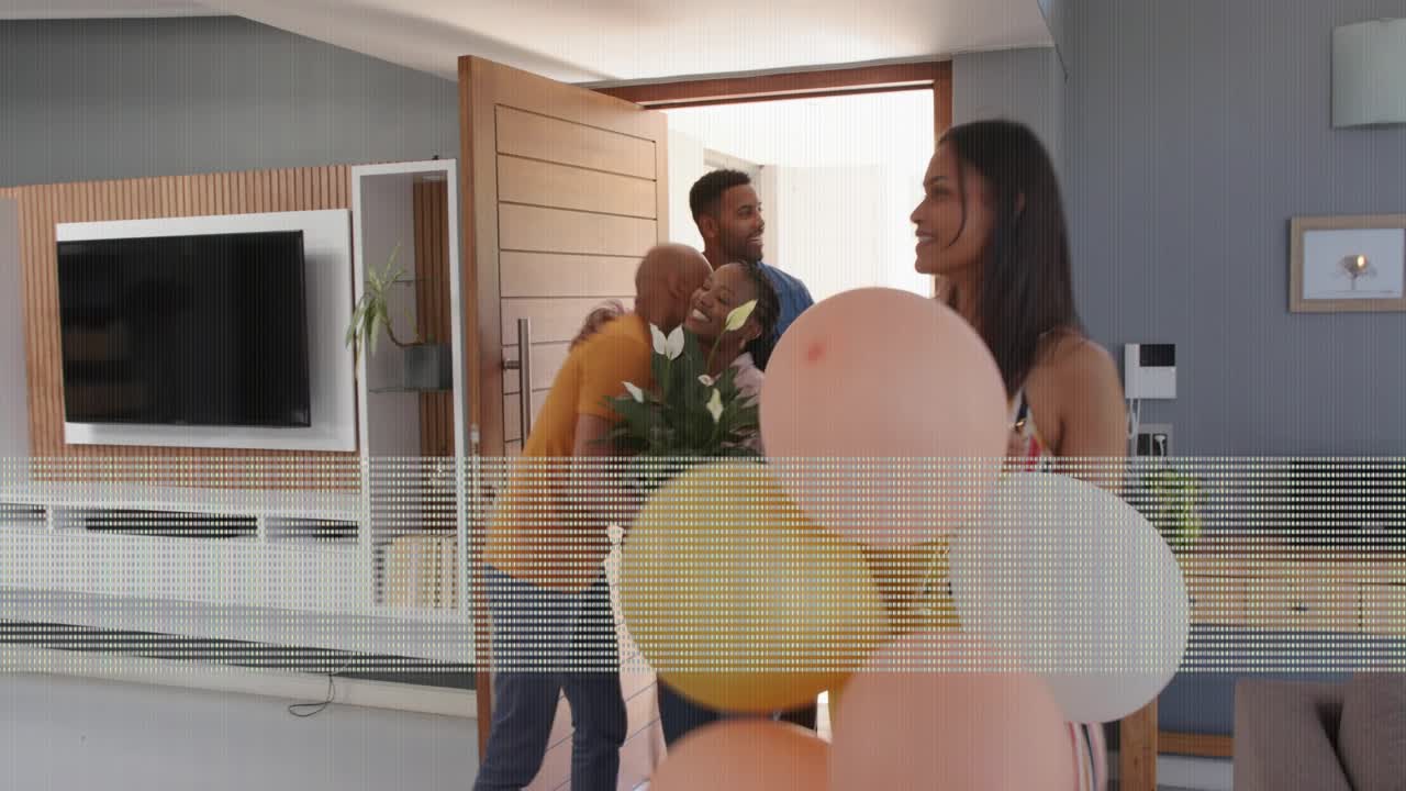 Una persona apre la porta d’ingresso in legno e accoglie amici in una casa moderna, accettando una pianta e dei palloncini