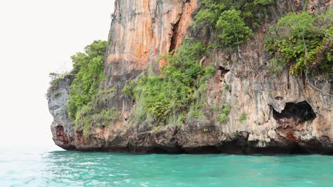 long-tail boat passing rocky cliffs and islands