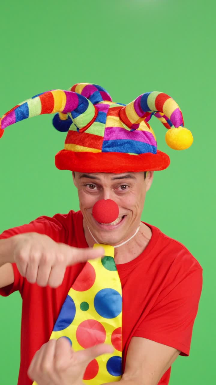 Clown pointing aside on green screen background