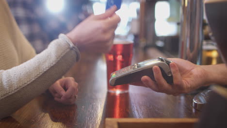 primer plano de una cliente femenina en un bar haciendo pago sin contacto para bebidas en una pandemia de salud